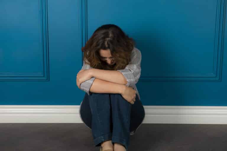 ילדה צעירה מדוכאת יושבת על הרצפה ובוכה